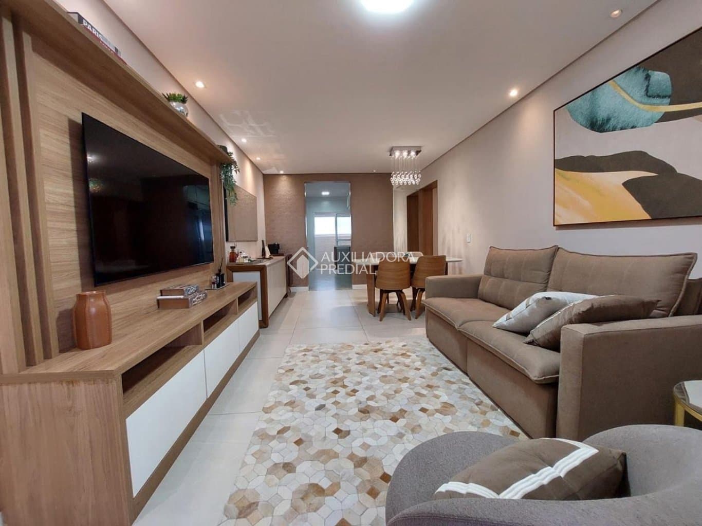 Sala de estar integrada com jantar, TV em painel de madeira e quadro decorativo na parede.