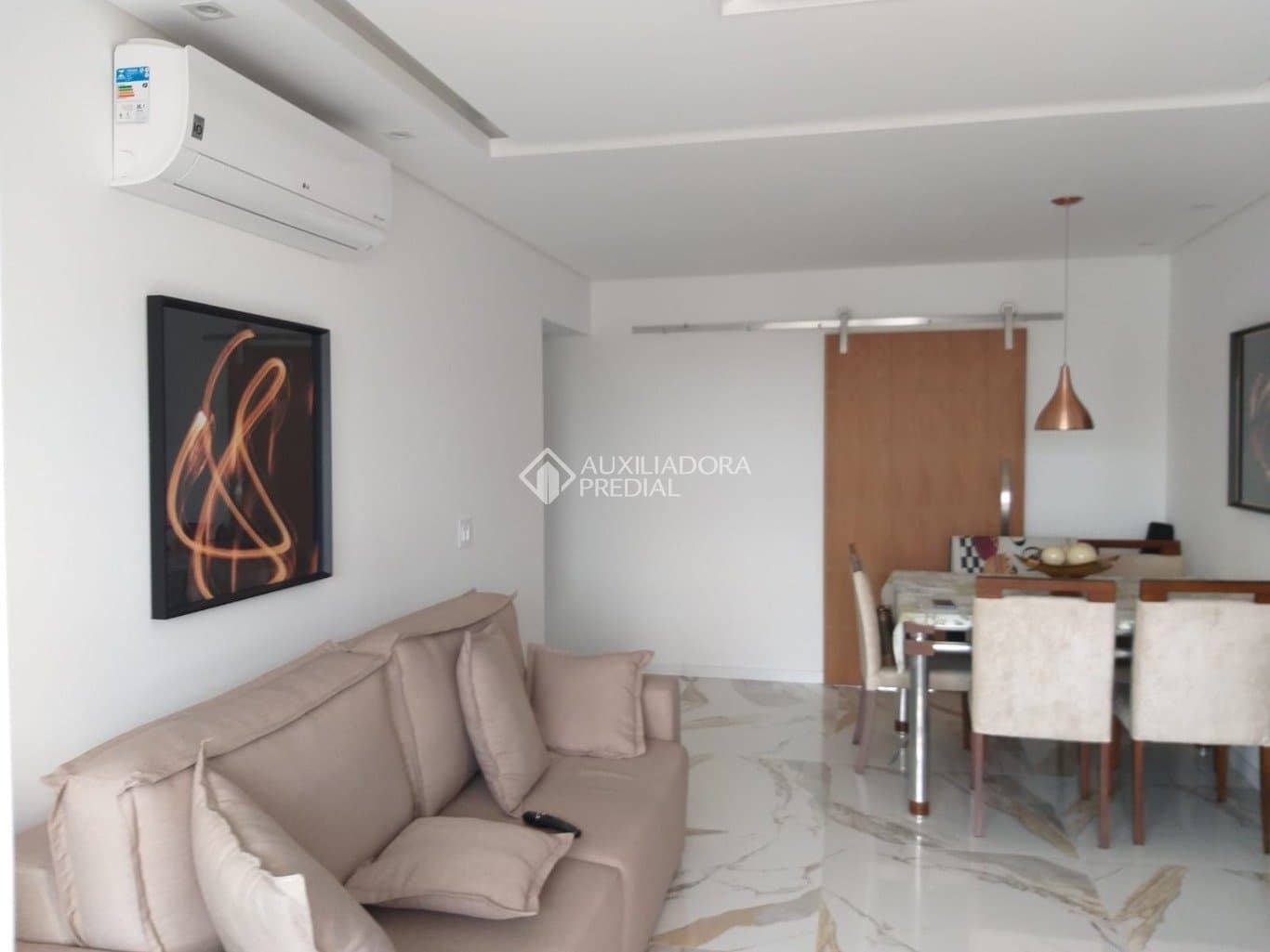 Sala de estar com sofá, ar-condicionado e quadro decorativo na parede.