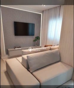 Sala de estar com sofá e painel ripado para TV.